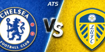 A wide split-screen sports banner featuring Chelsea on the left and Leeds United on the right. The Chelsea side has a textured blue background with the club’s circular crest prominently displayed, while the Leeds side uses a bright yellow textured background with the club’s shield badge. A glowing “VS” sits in the center dividing the two teams, with “ATS” positioned above it. Both crests have a slightly raised, polished look, and the design uses a diagonal light streak to separate the blue and yellow halves.