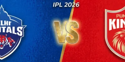 Wide IPL matchup graphic with a diagonal split background—deep blue on the left for Delhi Capitals and bright red on the right for Punjab Kings. Each side features its team logo prominently, with a glowing gold “VS” in the center and “ATS IPL 2026” text above. Subtle star icons appear in the upper corners, and the overall design has a textured, high-energy sports poster style.