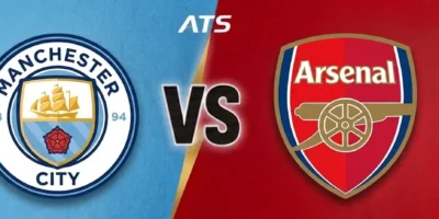 A split-screen graphic for a Manchester City vs Arsenal match prediction, featuring the Manchester City club crest on a textured sky blue background and the Arsenal club crest on a textured red background, separated by a central VS logo.