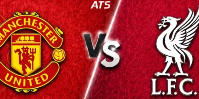 Wide horizontal match preview banner showing Manchester United vs Liverpool, split diagonally with deep red textured backgrounds. Manchester United’s crest is on the left, Liverpool’s liver bird logo with “L.F.C.” on the right, with a glowing “VS” in the center and “ATS” text at the top.