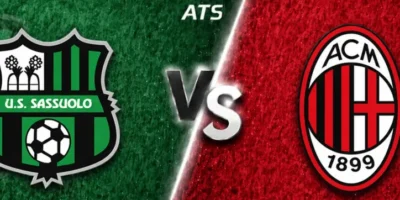 Wide horizontal match preview banner showing Sassuolo vs AC Milan, split diagonally with green and red textured backgrounds. Sassuolo’s crest is on the left, AC Milan’s oval crest on the right, with a glowing “VS” in the center and “ATS” text at the top.