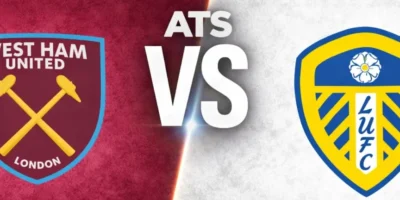 A wide sports matchup graphic featuring West Ham United and Leeds United facing off. West Ham United’s crest appears on the left over a textured claret background with faint oversized club branding in the backdrop, while Leeds’s crest is displayed on the right over a textured white background with a faded club logo watermark. A glowing diagonal divider separates the two sides, with large metallic “VS” lettering centered between the clubs. The design uses dramatic lighting, textured patterns, and soft gray borders above and below for a polished promotional match graphic.