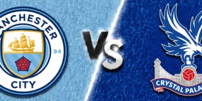 A wide sports matchup graphic featuring Manchester City and Crystal Palace facing off. Manchester City’s crest appears on the left over a textured sky-blue background with a faint oversized club watermark in the backdrop, while Crystal Palace’s crest is displayed on the right over a deep royal blue textured background with faded club branding. A glowing diagonal divider separates the two sides, with large metallic “VS” lettering centered between the clubs. The design uses dramatic lighting, textured patterns, and soft gray borders above and below for a polished promotional match graphic.